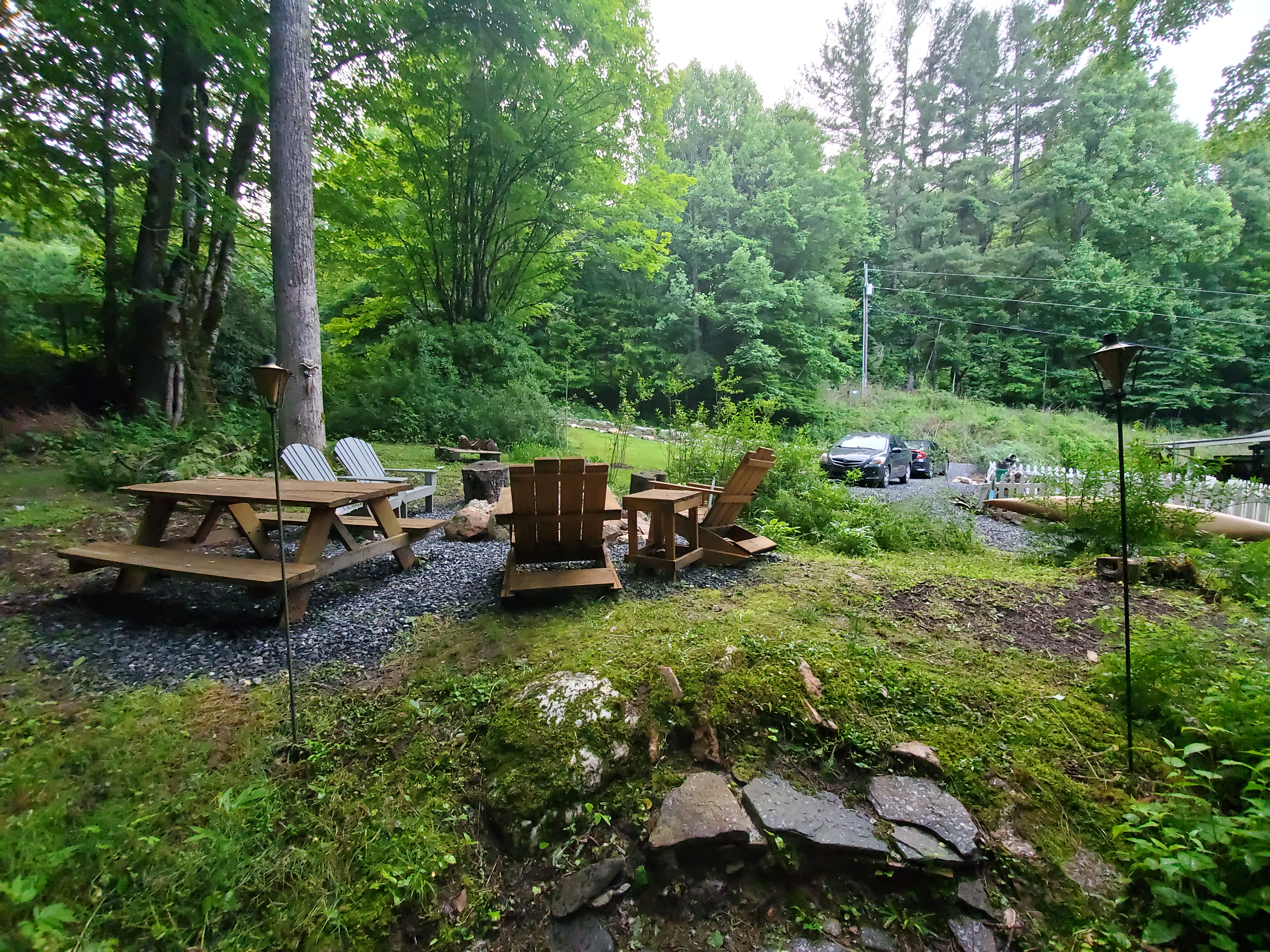 Backyard before — bare grass and gravel with a basic fire ring