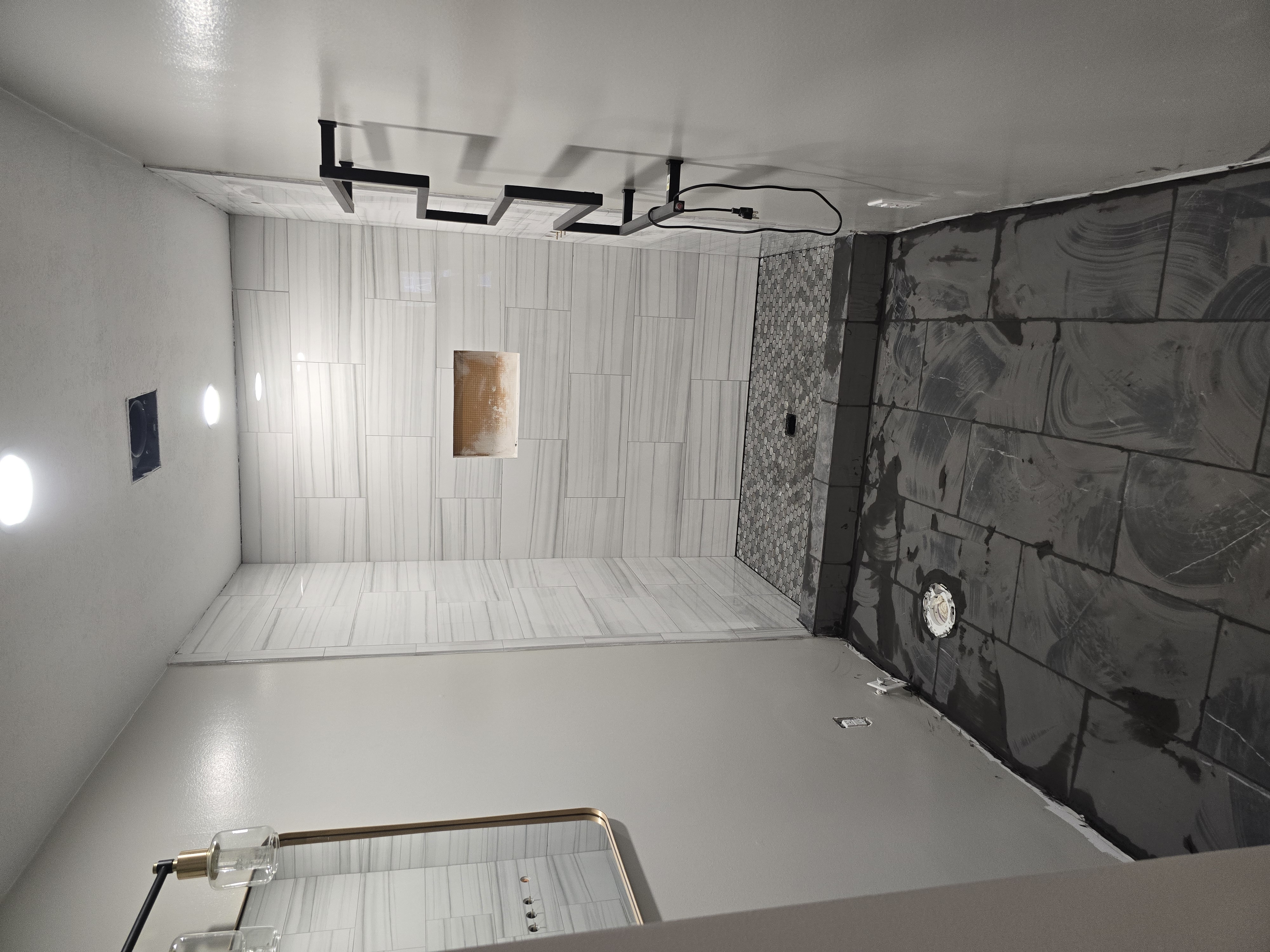 Walk-in shower — tiled floor-to-ceiling in marble-look porcelain with a mosaic floor and niche