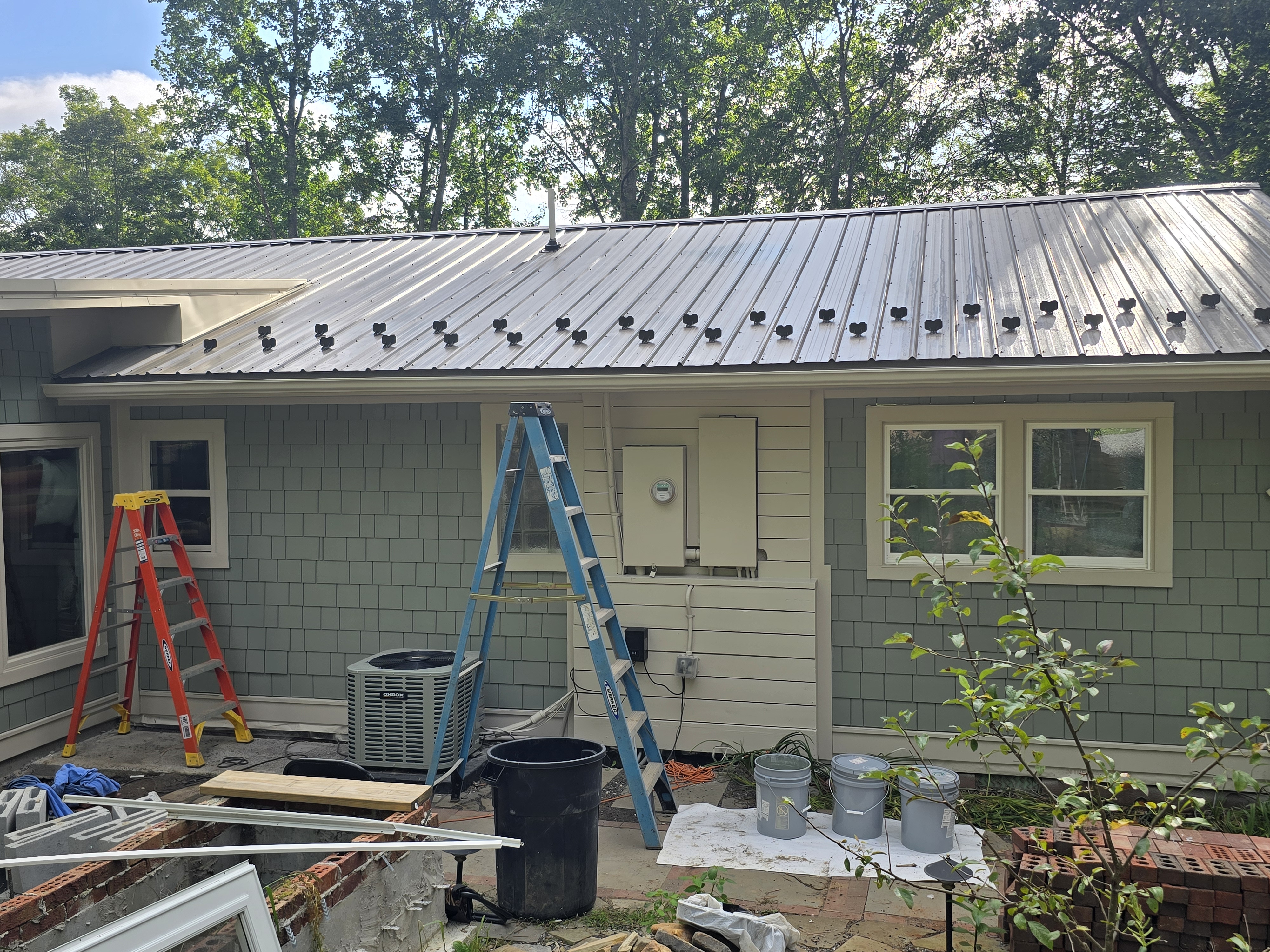 Exterior rebuild in progress — standing-seam metal roof installed over a wrapped structure