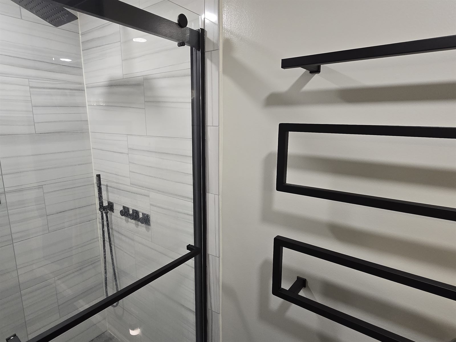 Finished walk-in shower with black-framed glass enclosure and matte-black fixtures