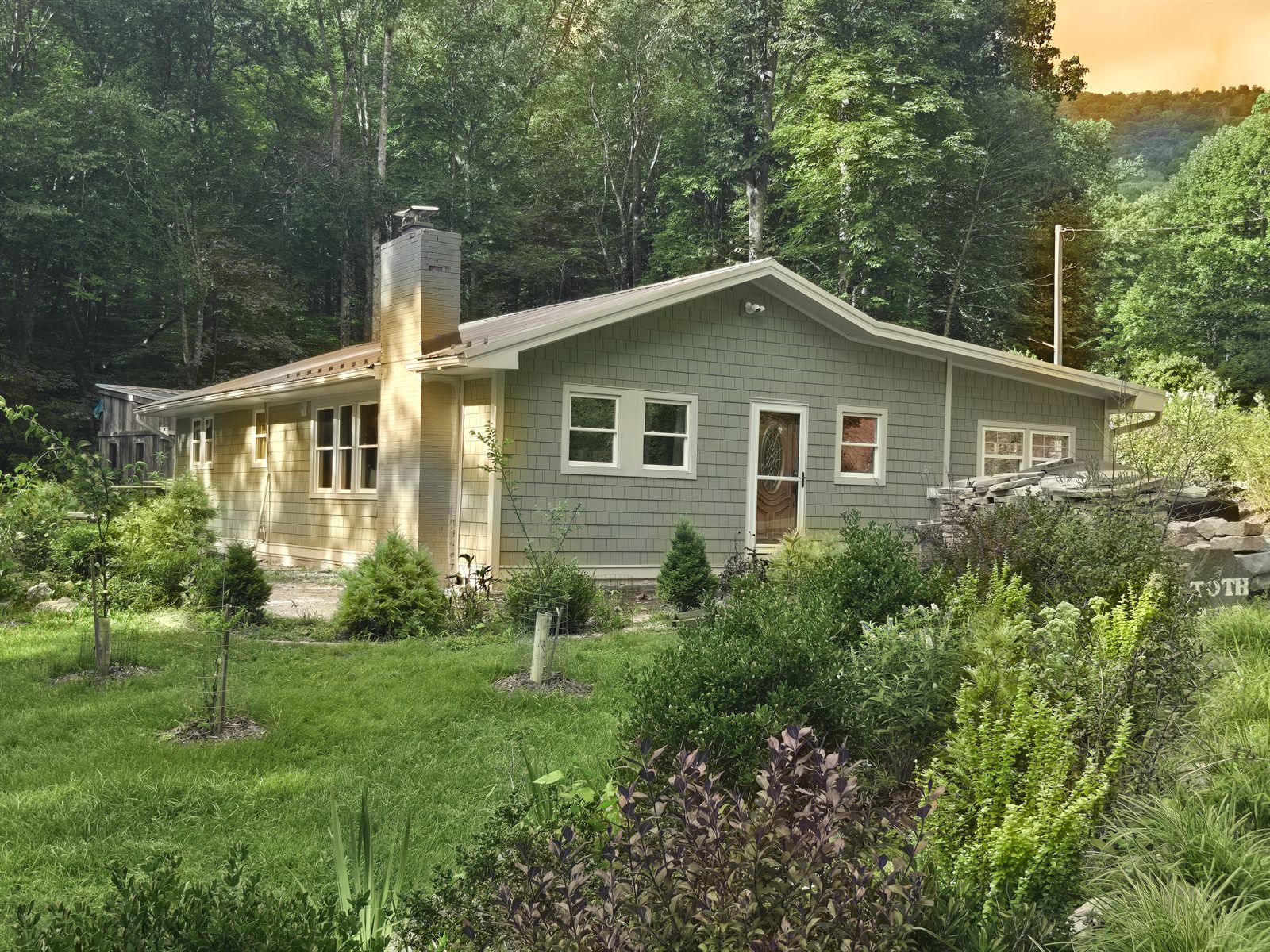 Home exterior after — finished shake siding, standing-seam metal roof, and new landscaping